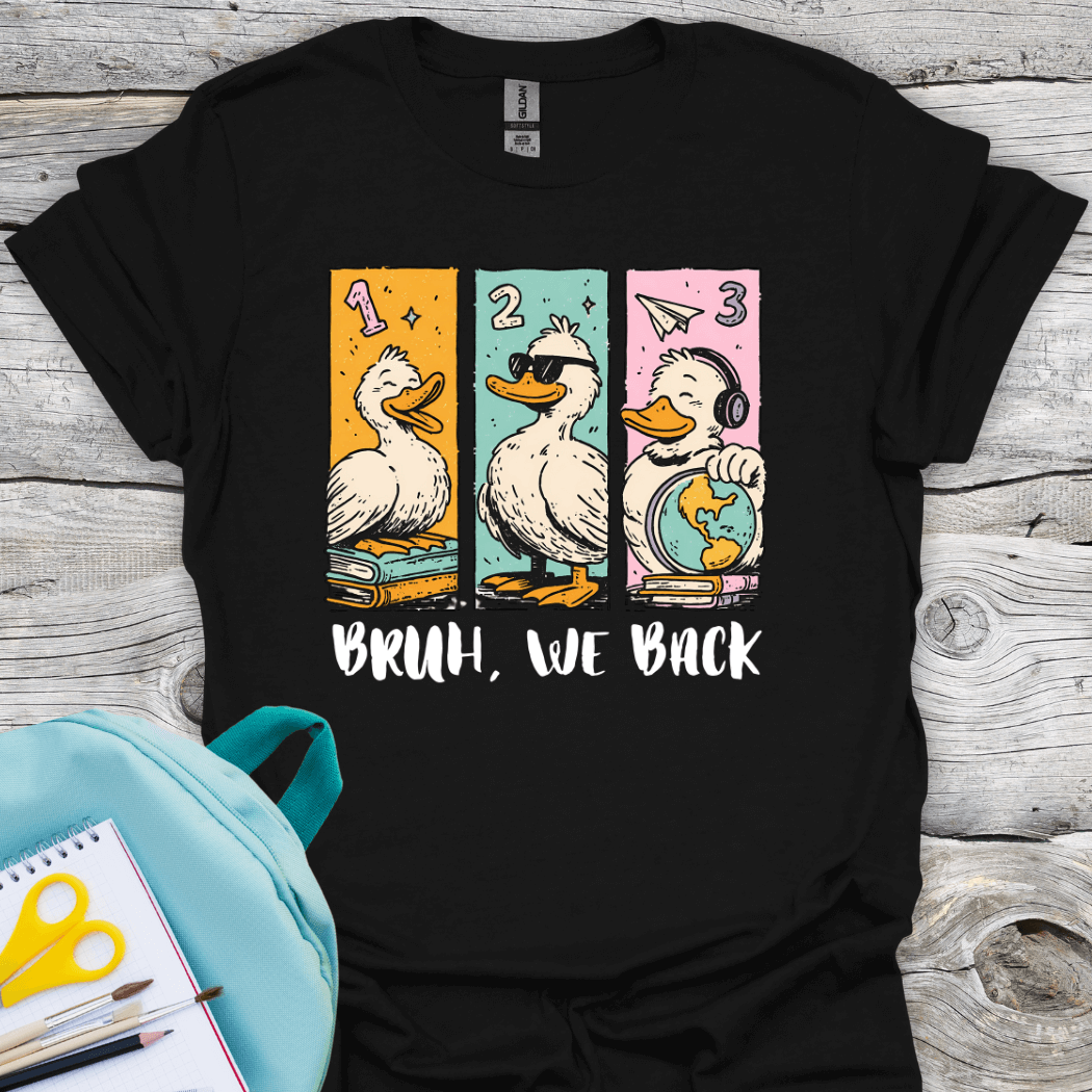 Black t-shirt with graphic design of three ducks and text 'BRUH, WE BACK' on a wooden surface.