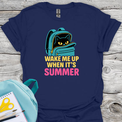Navy blue t-shirt with a cat in a backpack graphic and 'Wake Me Up When It's Summer' text on a wooden surface.